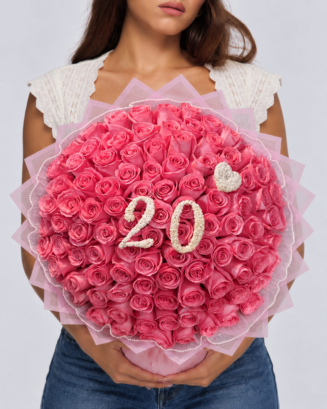 Bouquet Kikky de roses rose vif fraîches avec chiffre 20 blanc, porté par une femme