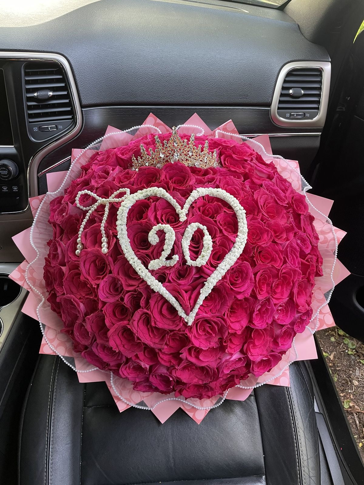 Bouquet Kikky de roses roses avec chiffre 20 dans un cœur décoratif sur un siège de voiture