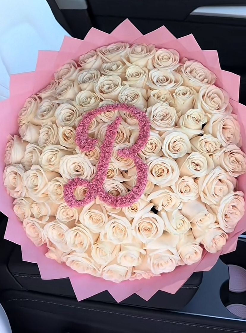 Bouquet Lyra de roses blanches fraîches avec lettre B, papier rose, dans une voiture