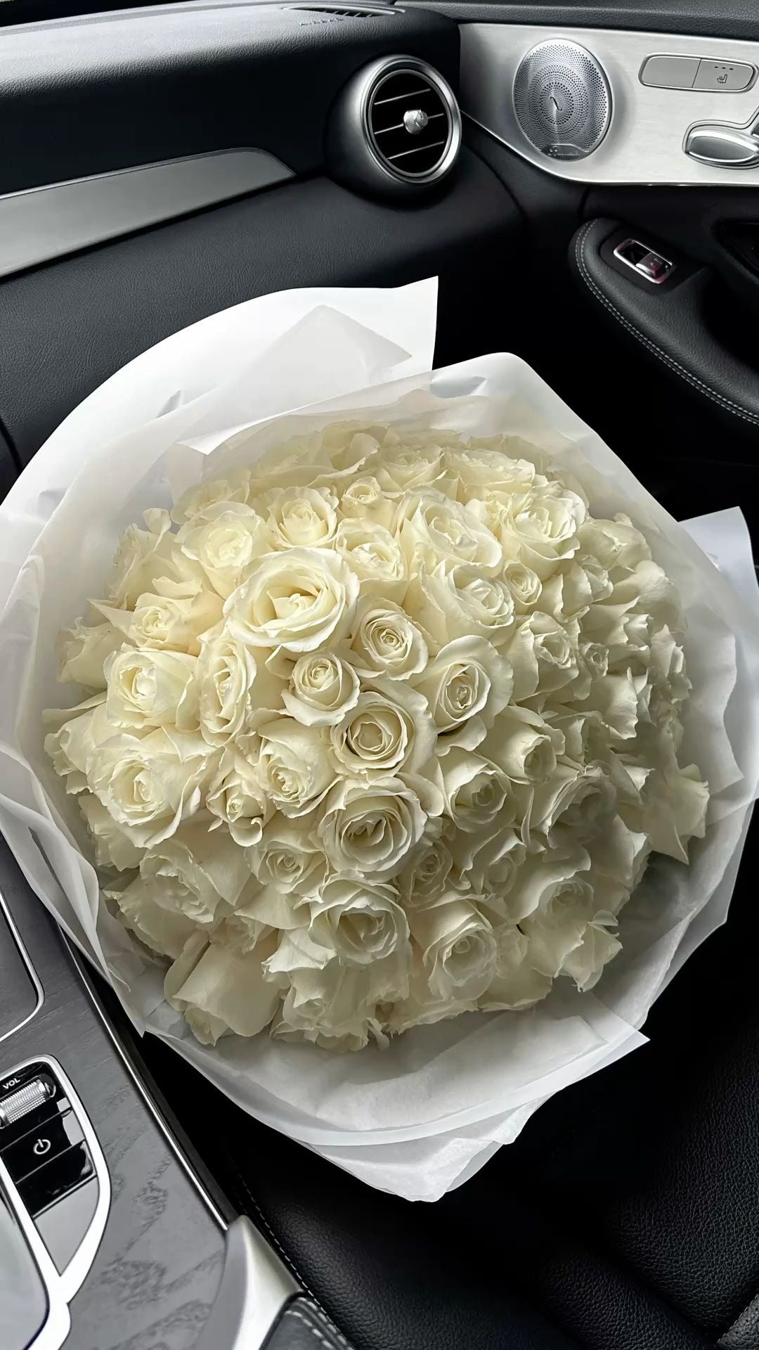Bouquet Lyra de roses blanches fraîches en papier blanc, dans une voiture