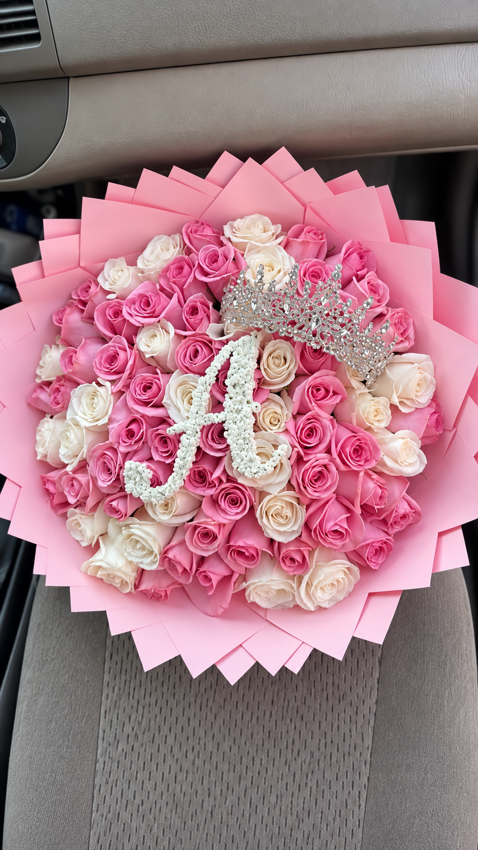 Bouquet Mademoiselle de roses blanches et roses fraîches avec lettre, papier rose, dans une voiture