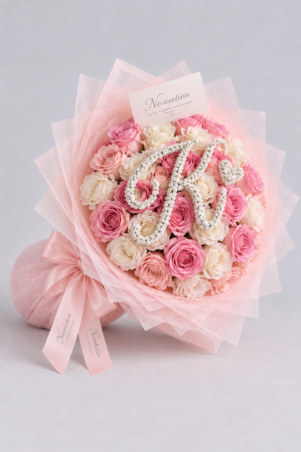 Bouquet Mademoiselle de roses blanches et roses fraîches, vue de côté avec nœud rose et lettre