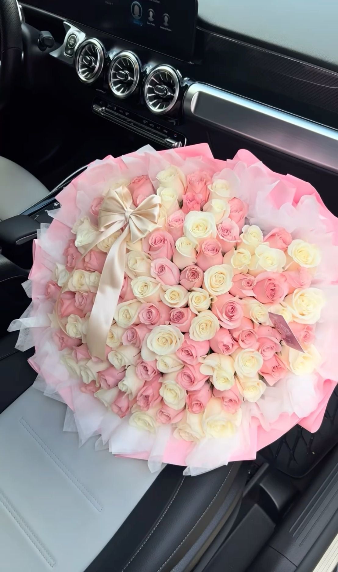 Bouquet Mademoiselle de roses blanches et roses fraîches avec nœud crème, dans une voiture