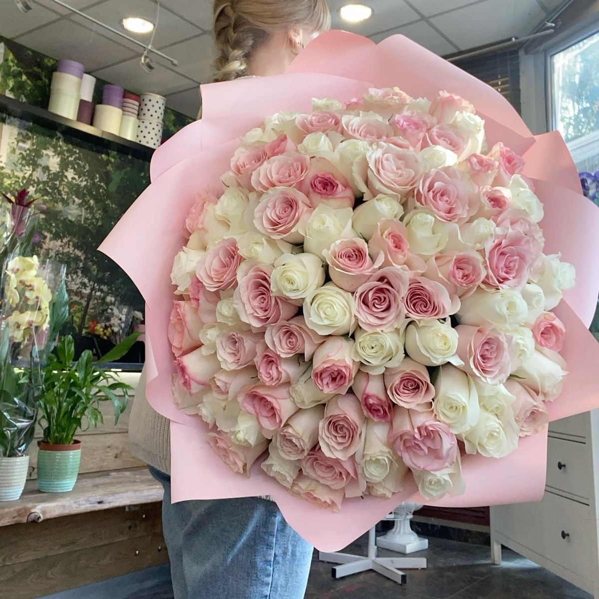 Très grand bouquet Mademoiselle de roses blanches et roses fraîches, papier rose, tenu dans les bras