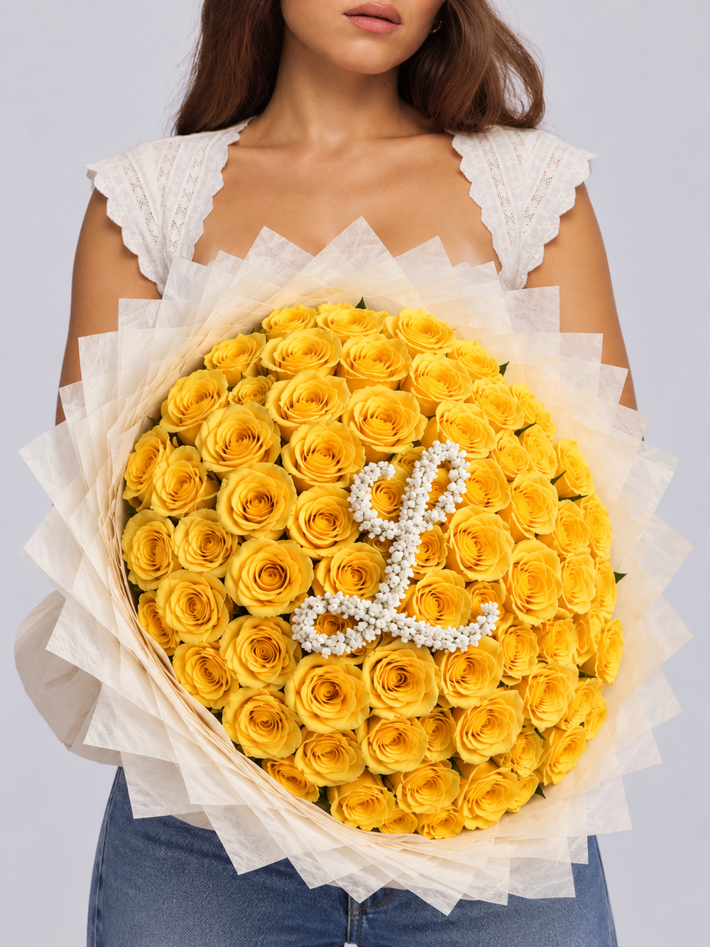 Bouquet Mia de roses jaunes fraîches avec lettre L, papier blanc crème, porté par une femme