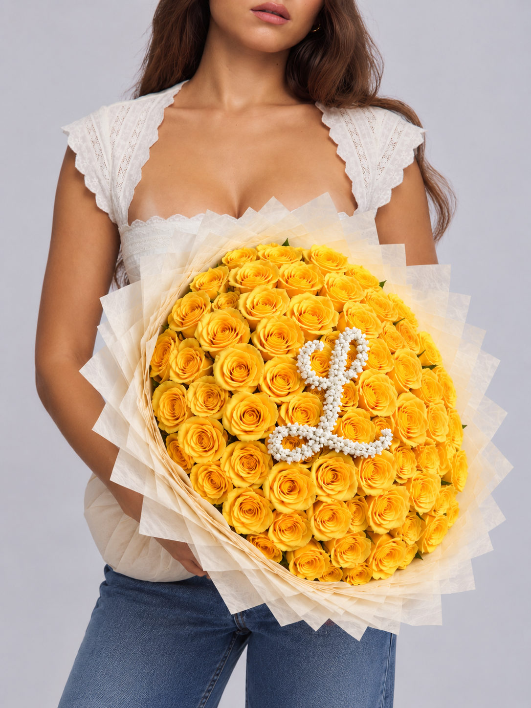 Bouquet Mia de roses jaunes avec lettre L tenu dans les bras, vue de côté