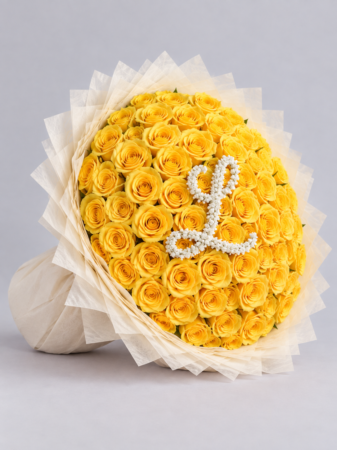 Bouquet Mia de roses jaunes avec lettre L posé sur fond clair, vue de côté