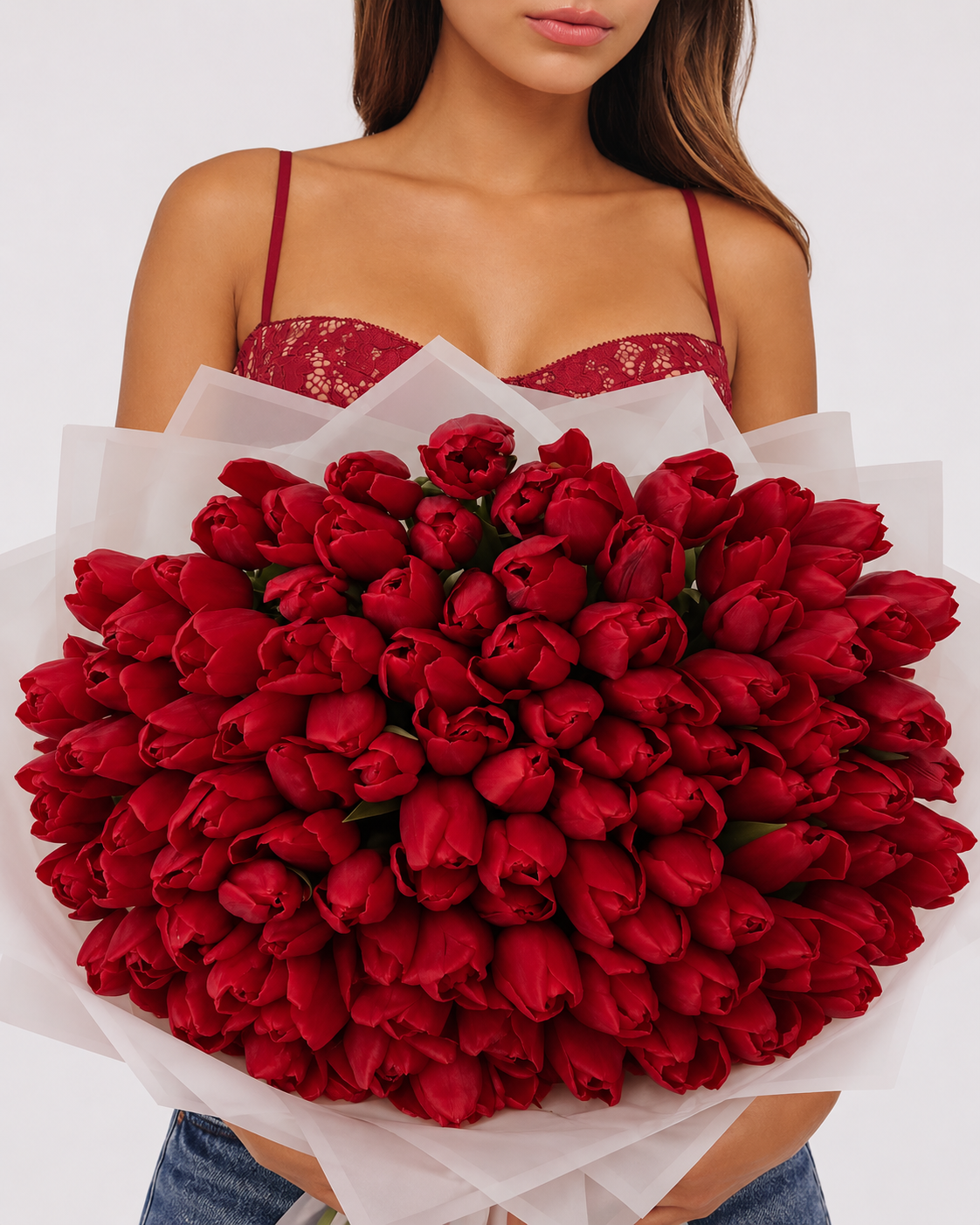 Bouquet Mira de tulipes rouges fraîches porté par une femme, papier blanc translucide