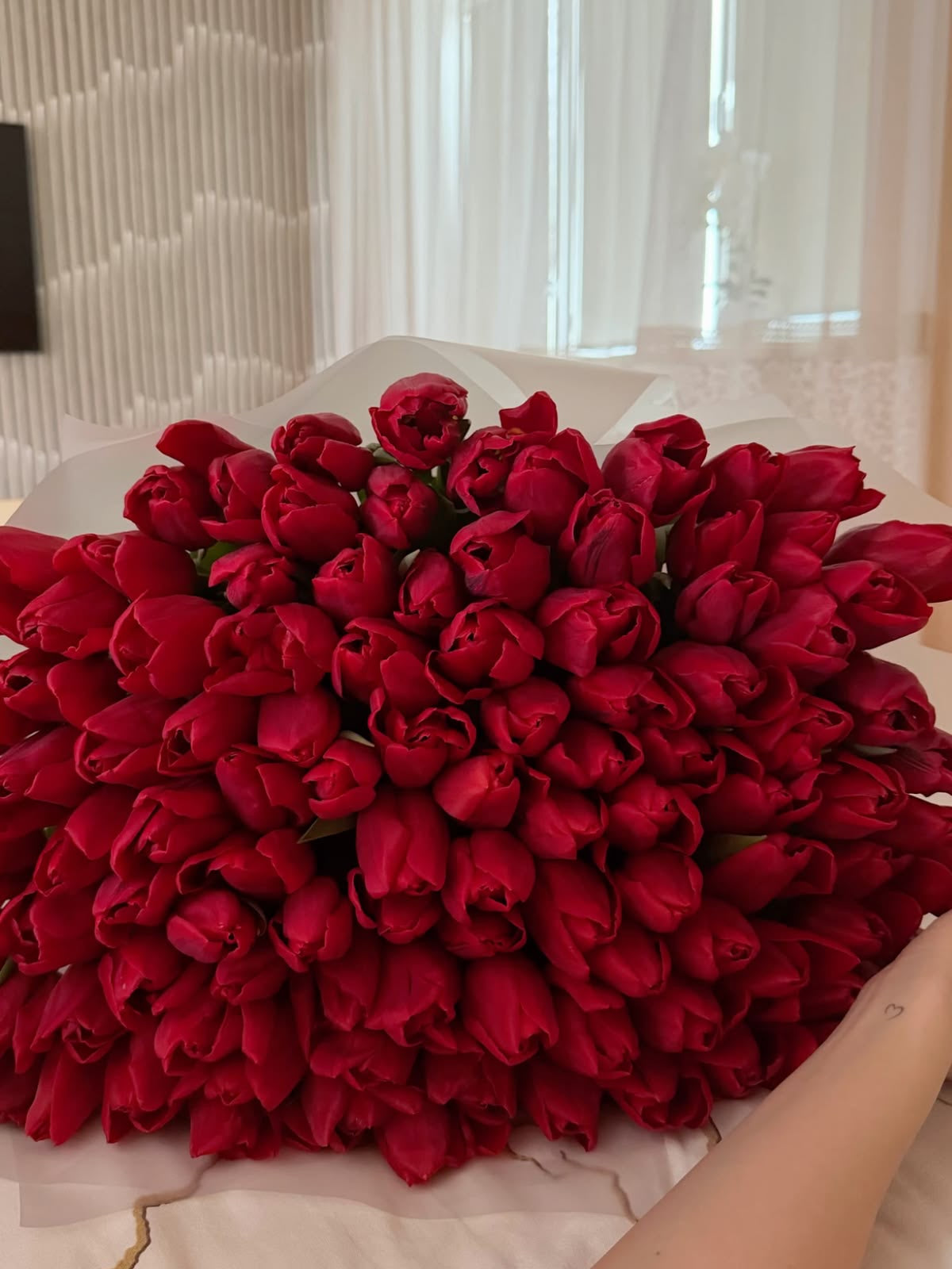 Bouquet Mira de tulipes rouges très fourni posé sur un lit