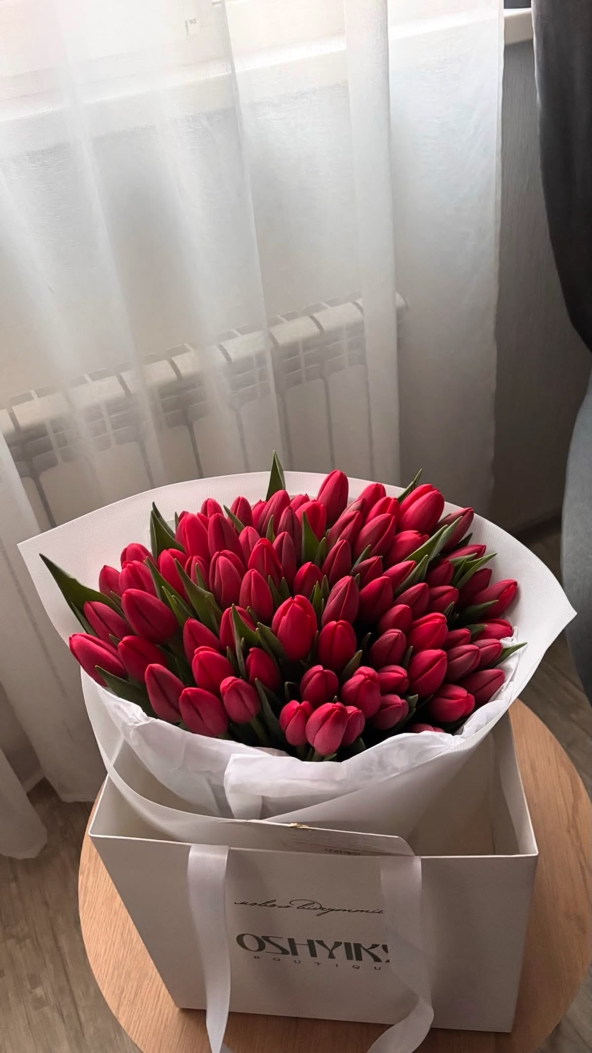 Bouquet Mira de tulipes rouges posé sur une boîte blanche, mise en scène