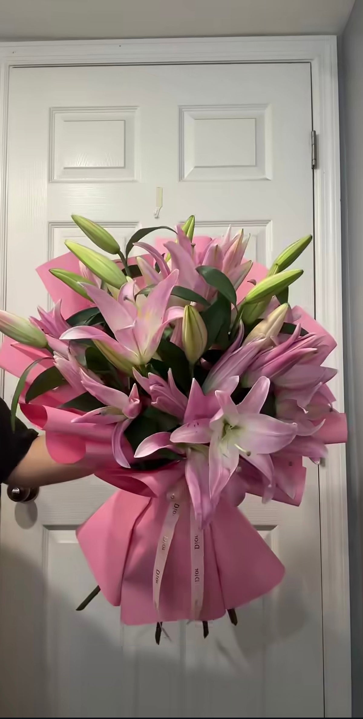 Bouquet Muse de lys roses et roses roses devant une porte blanche