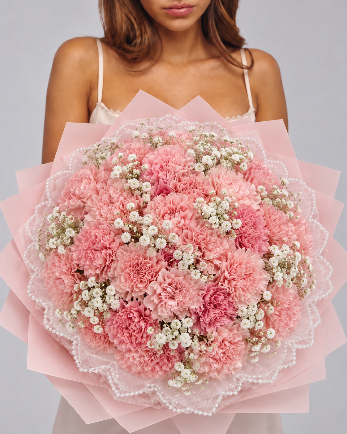 NORAH, bouquet rond d'œillets roses et gypsophile blanche tenu à la main