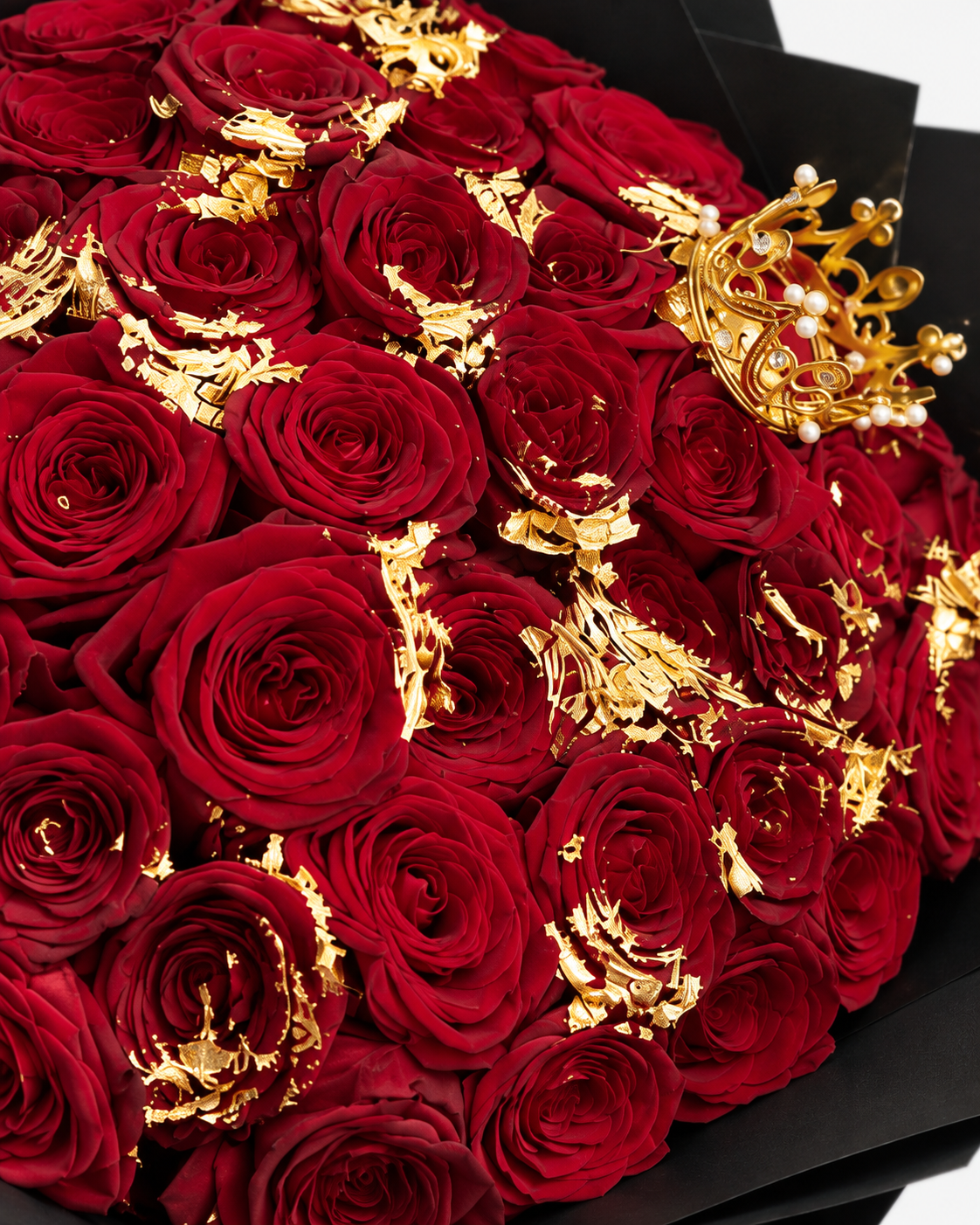 Gros plan sur les roses rouges fraîches et les feuilles d'or du bouquet ORNELA