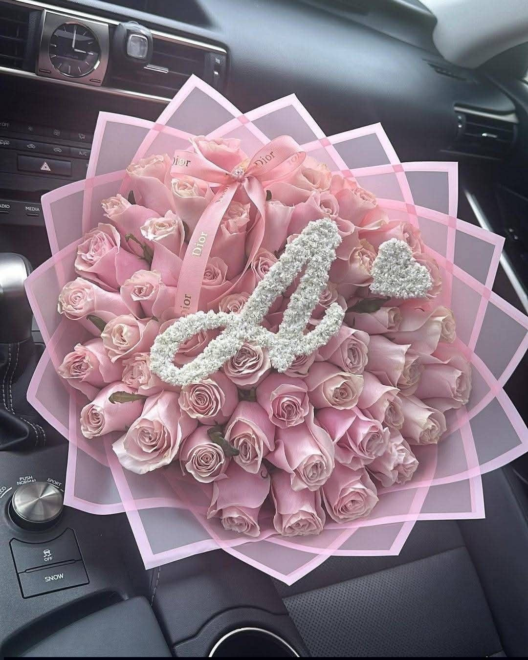 Bouquet Penelope de roses roses fraîches avec lettre A et cœur, papier rose, dans une voiture