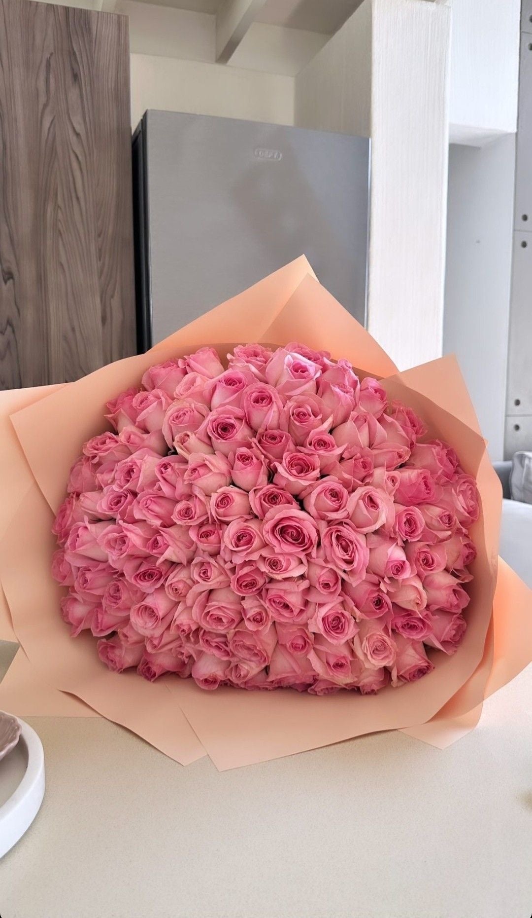 Bouquet Penelope de roses roses fraîches en papier kraft, posé sur un plan de travail