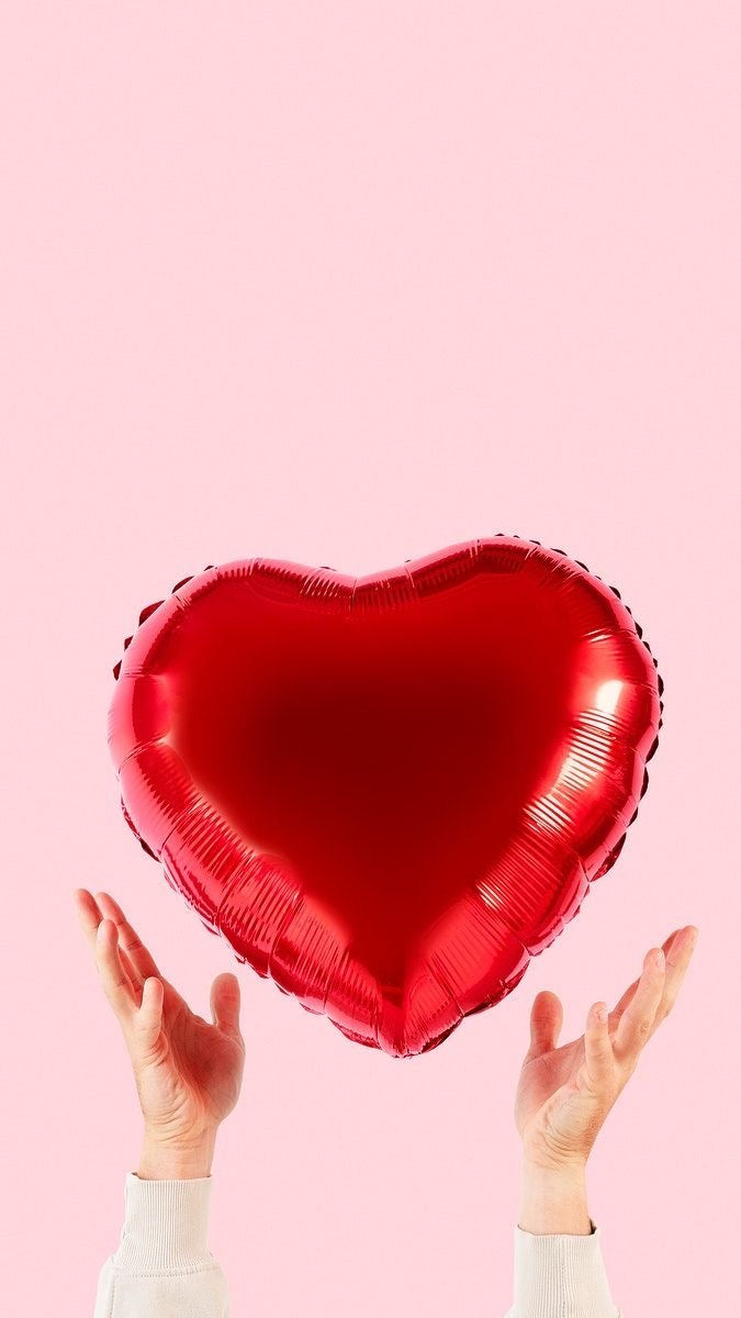 Ballon cœur rouge Petit Ballon Avec Amour tenu entre deux mains sur fond rose