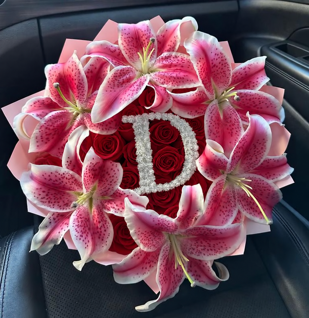Bouquet Selma de roses rouges et lys roses avec une initiale décorative au centre