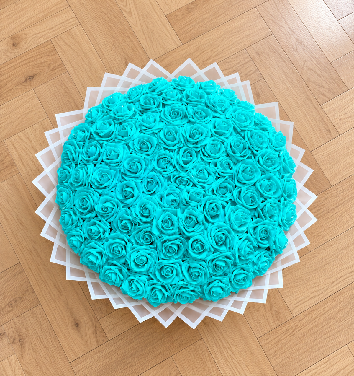Bouquet TIFFANY de 50 roses éternelles bleu turquoise posé sur un parquet