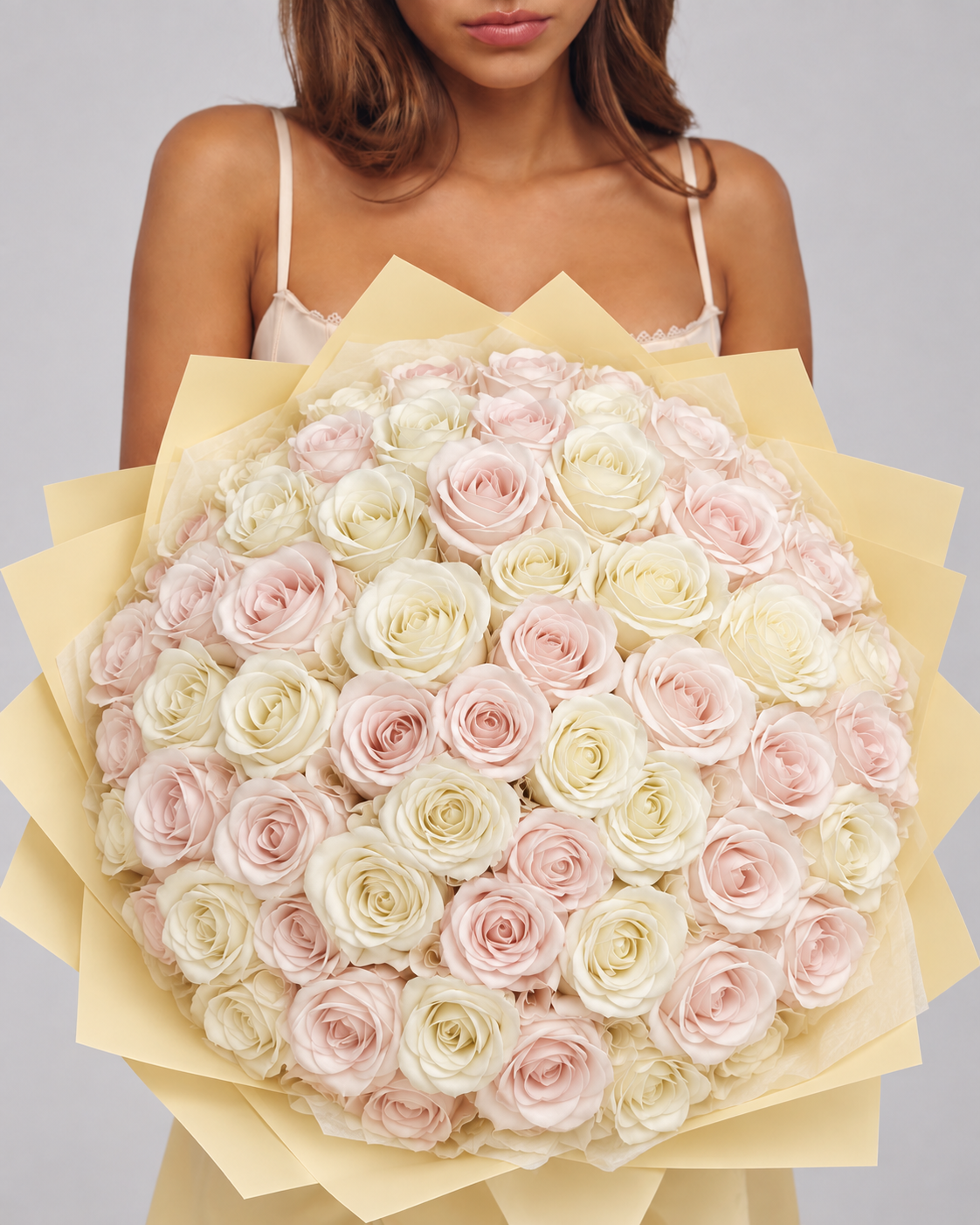 VANILLA, bouquet de 50 roses éternelles rose pâle et blanc crème, tenu à la main